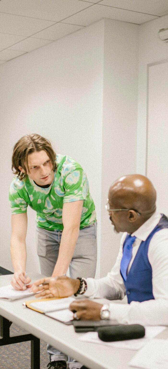 Young man discussing with diverse colleague during business meeting, collaboration, teamwork, consulting.