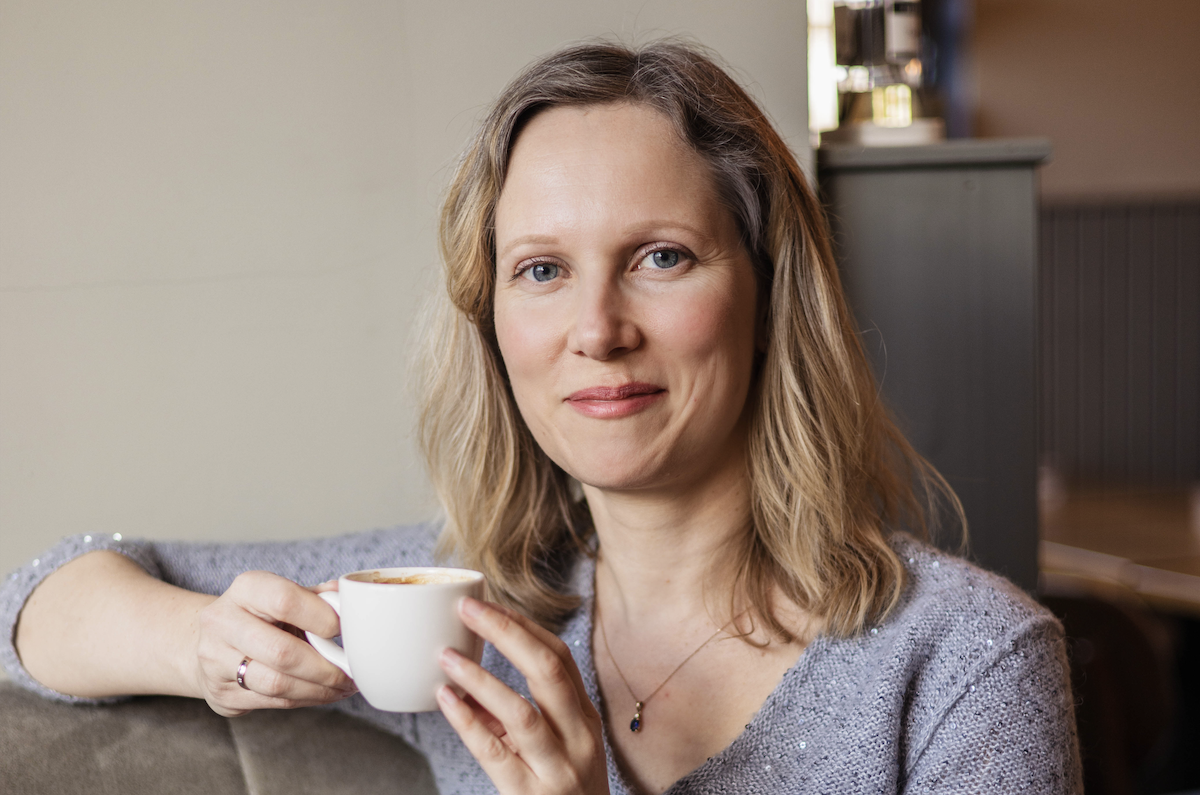 Warm woman enjoying coffee in a cozy cafe, representing comfort and relaxation.